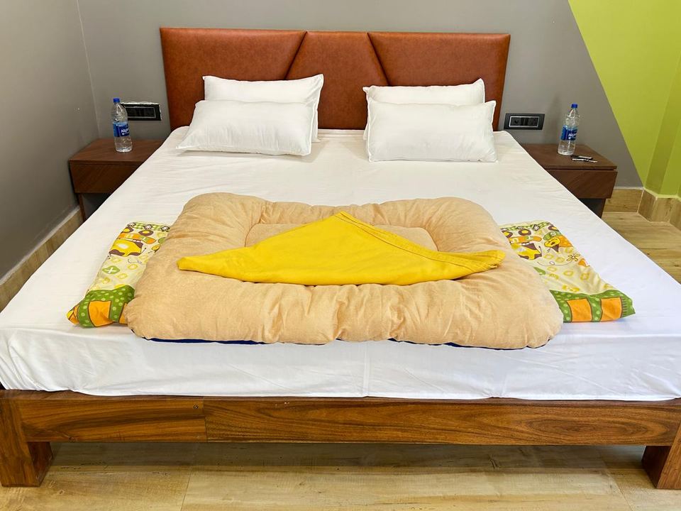 Made-up cottage bed with tan leather headboard and white linen at Chamtaburu Eco Village, Ajodhya Hills