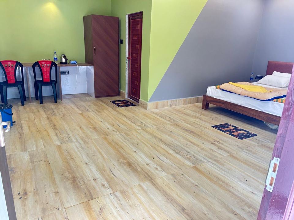 Wide cottage bedroom interior showing bed, desk area and wood floor at Chamtaburu Eco Village, Ajodhya Hills